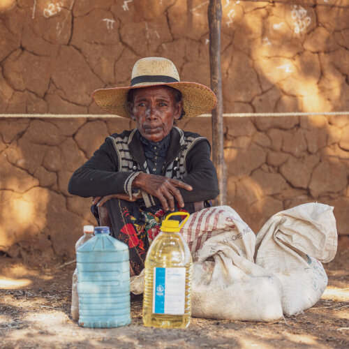 Woman sitting with bags and WFP oil container in front